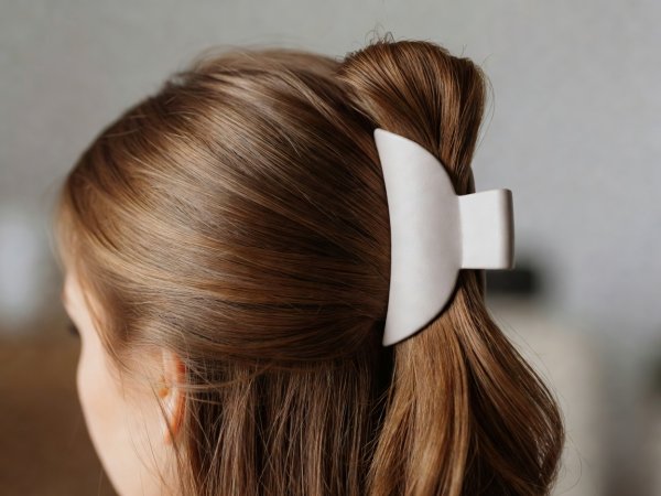 Shallow depth close-up of hair folded upward and anchored vertically with a matte jaw clip